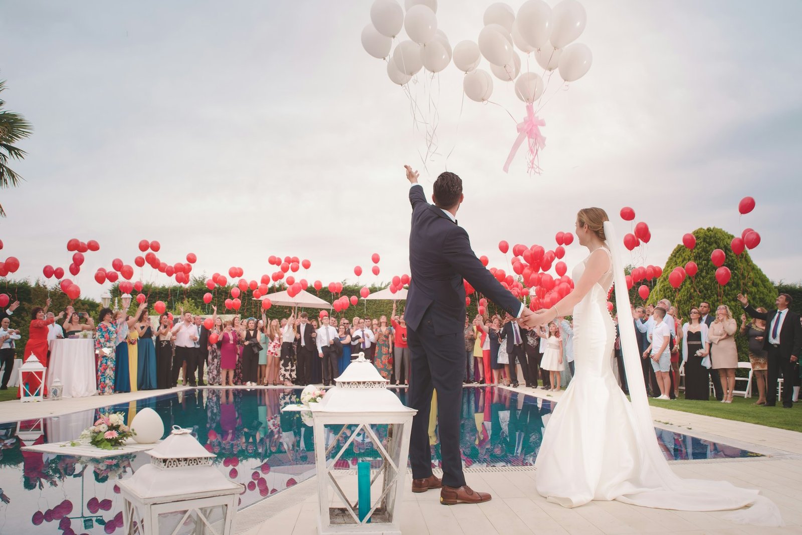 Couple releasing balloons beside a villa pool at golden hour